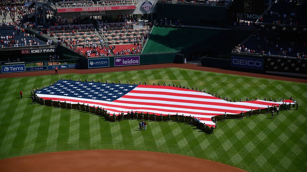 An American flag in the shape of the continental United States is displayed on the field before a baseball game between the Washington Nationals and the Boston Red Sox, Friday, July 4, 2025, in Washington. (AP Photo/Nick Wass)