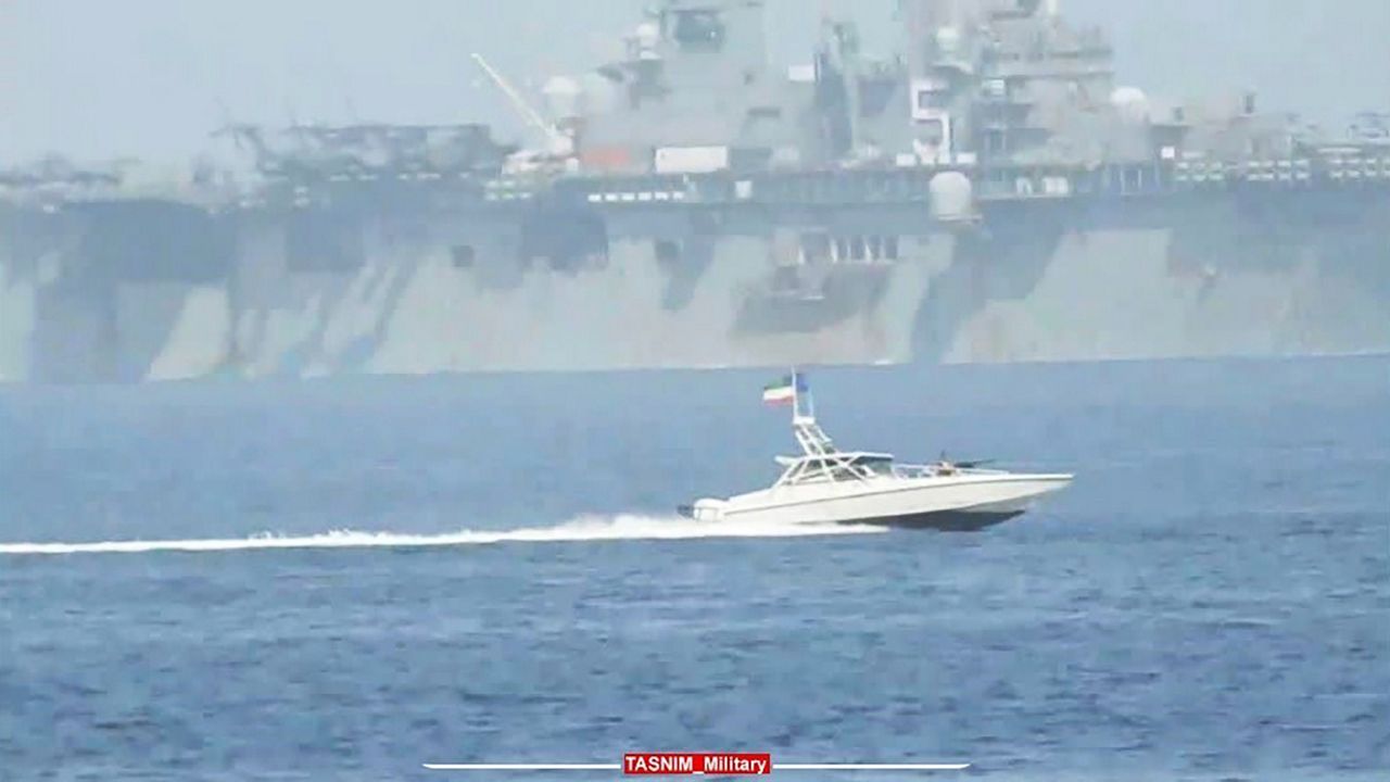 In this image provided by the Iranian Revolutionary Guard via Tasnim News agency on Sunday, Aug. 20, 2023, a Revolutionary Guard speedboat moves near USS Bataan at the Strait of Hormuz, in the mouth of the Persian Gulf. (Iranian Revolutionary Guard/Tasnim News Agency via AP)