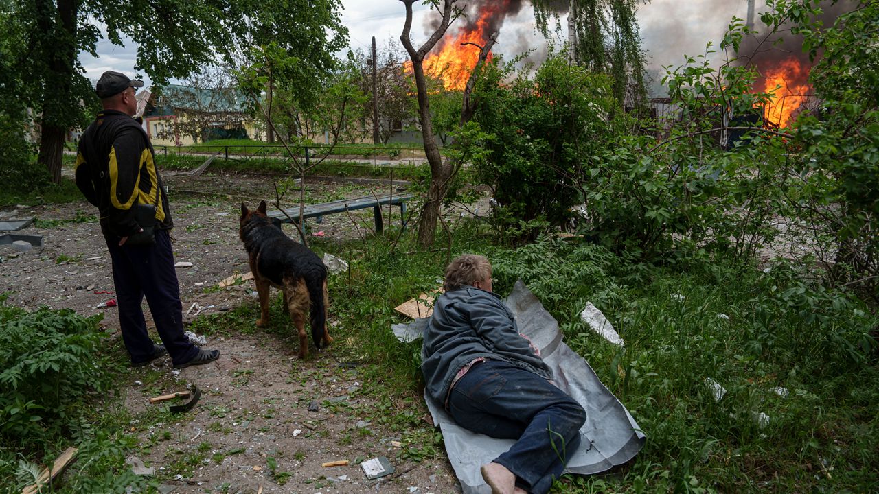 A man lies on the ground as he watches his burning house destroyed by a Russian airstrike in Vovchansk, Ukraine, on Saturday, May 11, 2024. (AP Photo/Evgeniy Maloletka)