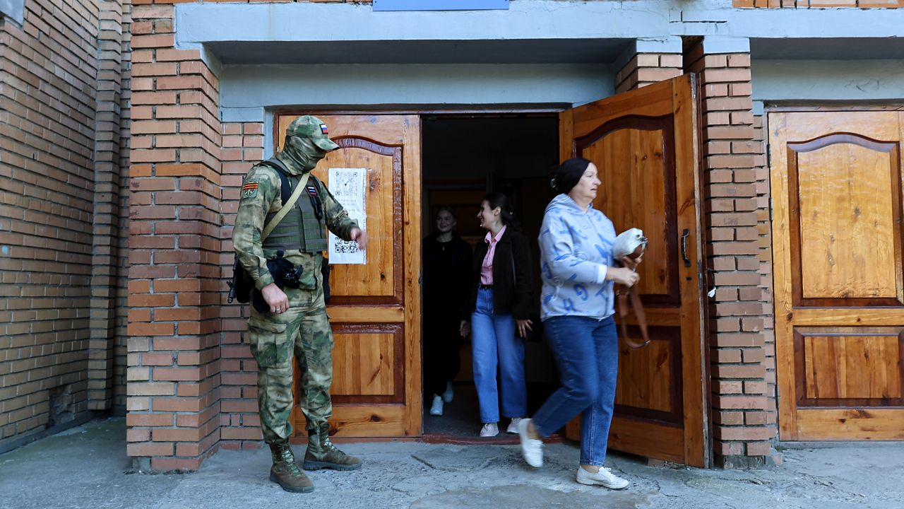 A serviceman guards an entrance of a polling station during a local elections in Donetsk, the capital of Russian-controlled Donetsk region, eastern Ukraine, on Sunday, Sept. 10, 2023. (AP Photo)