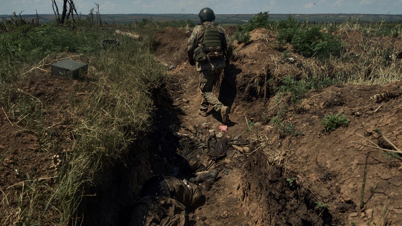 A Ukrainian soldier goes in a recently captured Russian trench with dead Russian soldiers, on the frontline near Bakhmut, Donetsk region, Ukraine, Tuesday, July 4 2023. (AP photo/Libkos, File)