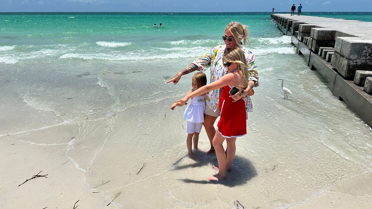 Paris Hoisington, 31, and her daughter Josie Law, 11, point to the area on Cortez Beach in Manatee County where the girl found a message in a bottle on Sunday (Spectrum News/Josh Rojas).