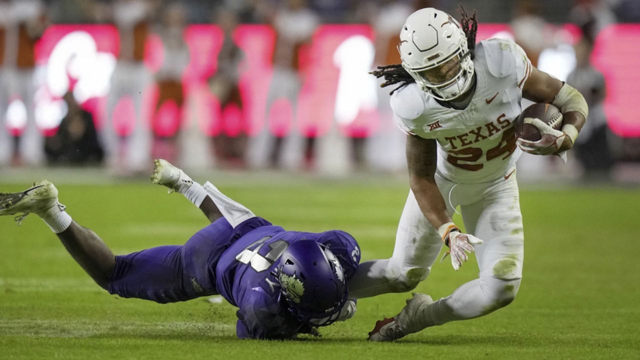 Texas running back Jonathon Brooks (24) is pulled down by TCU safety Mark Perry (3) late in the fourth quarter of an NCAA college football game, Saturday, Nov. 11, 2023, in Fort Worth, Texas. Brooks did not return to the game after limping off the field. (Ricardo B. Brazziell/Austin American-Statesman via AP)