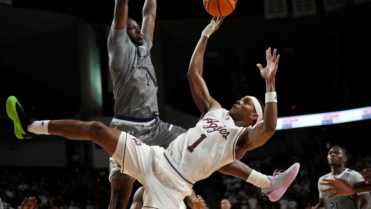 Texas A&M guard Zhuric Phelps (1) makes a basket over East Texas A&M guard Scooter Williams Jr. (1) during the first half of an NCAA college basketball game Friday, Nov. 8, 2024, in College Station, Texas. (AP Photo/Sam Craft)