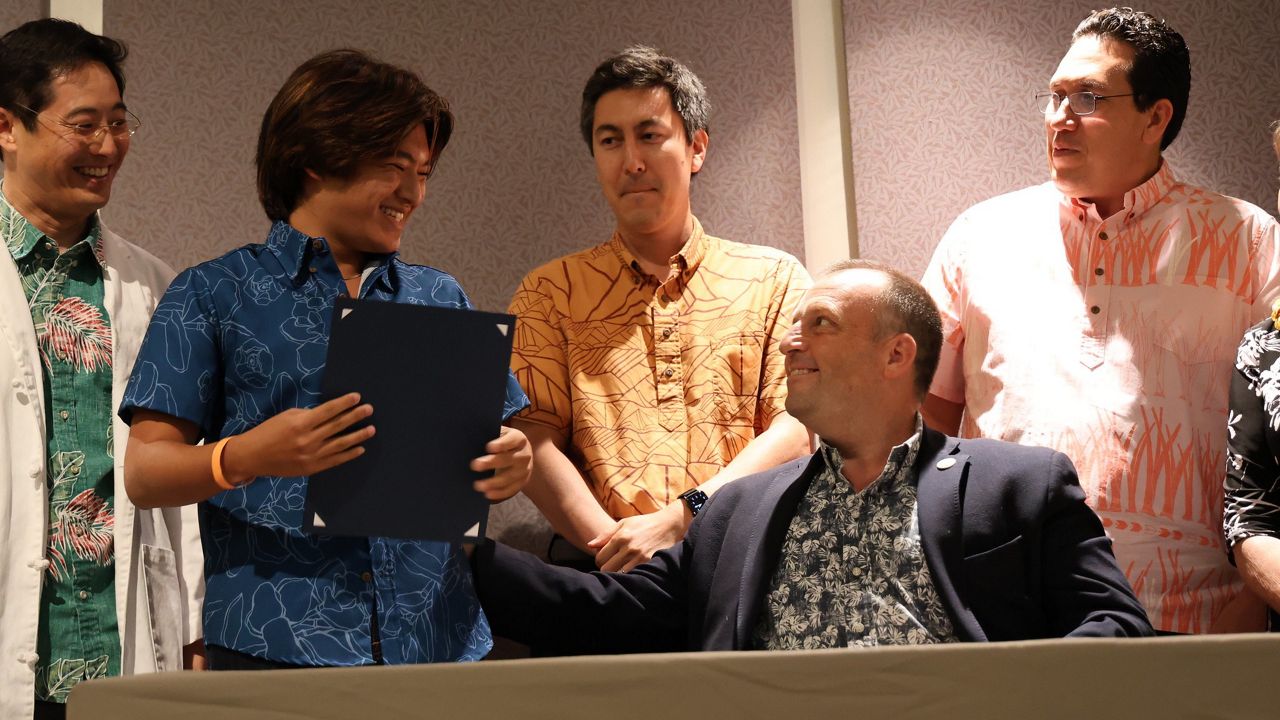 Gov. Josh Green shares a moment with youth advocate Josh Ching at Tuesday's bill signing ceremony at the State Capitol auditorium. (Photo courtesy of Office of Gov. Josh Green)