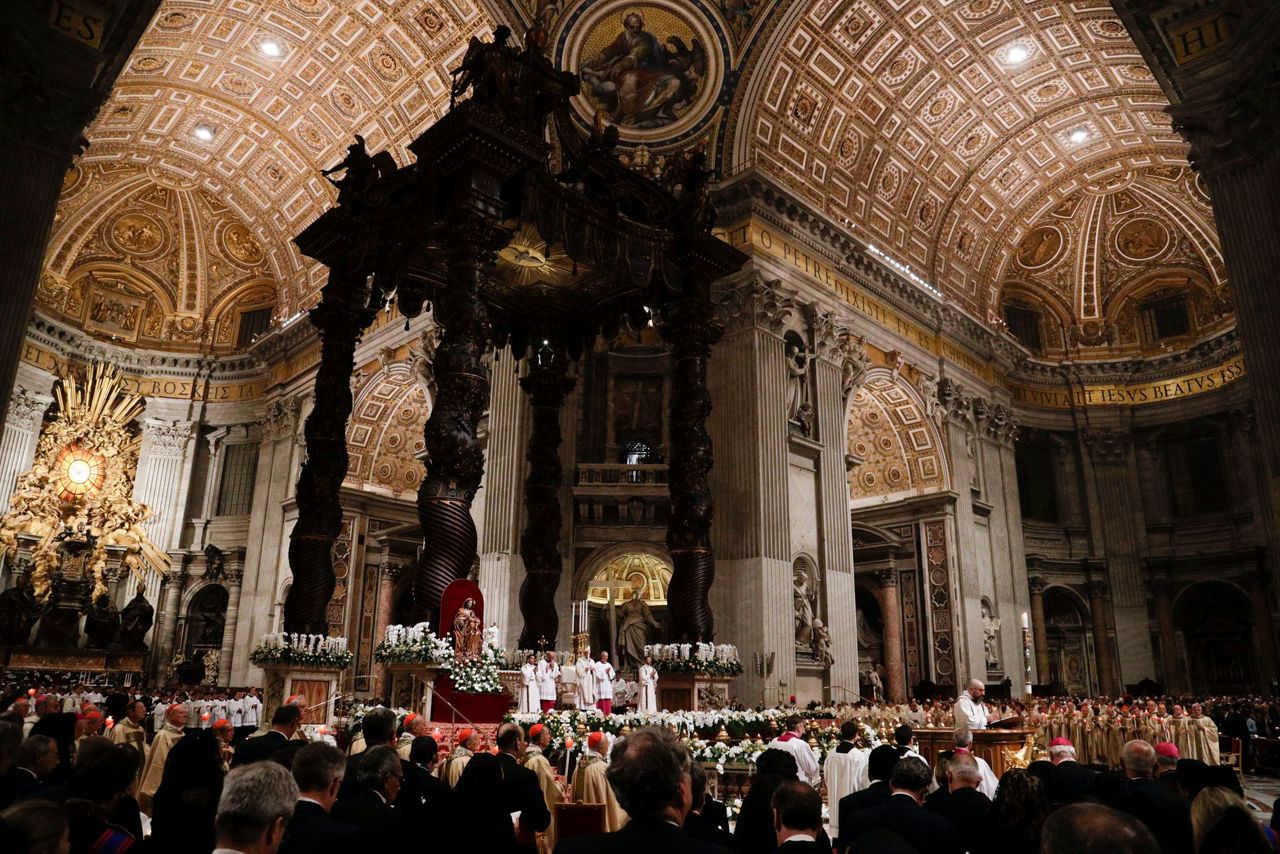 Pope carries Easter candle up aisle of darkened basilica