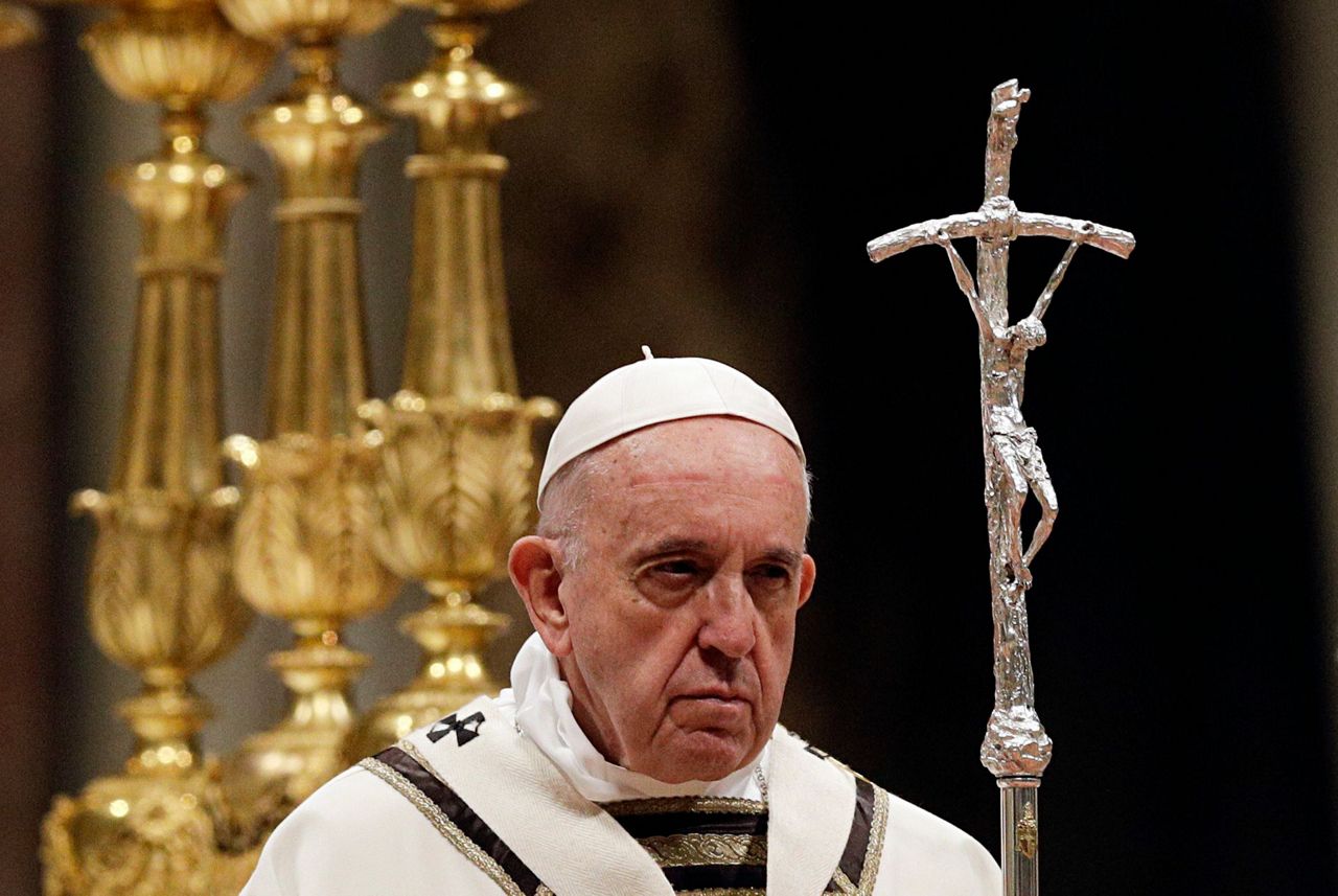 Pope carries Easter candle up aisle of darkened basilica