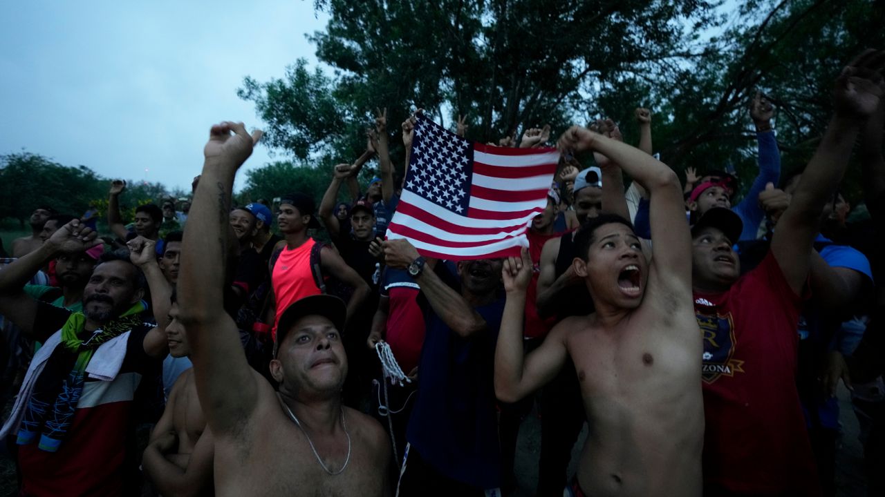 Venezuelan migrants wave a U.S. flag at a television helicopter that flew over the Rio Grande in Matamoros, Mexico on Friday, May 12, 2023, a day after pandemic-related asylum restrictions called Title 42 were lifted.