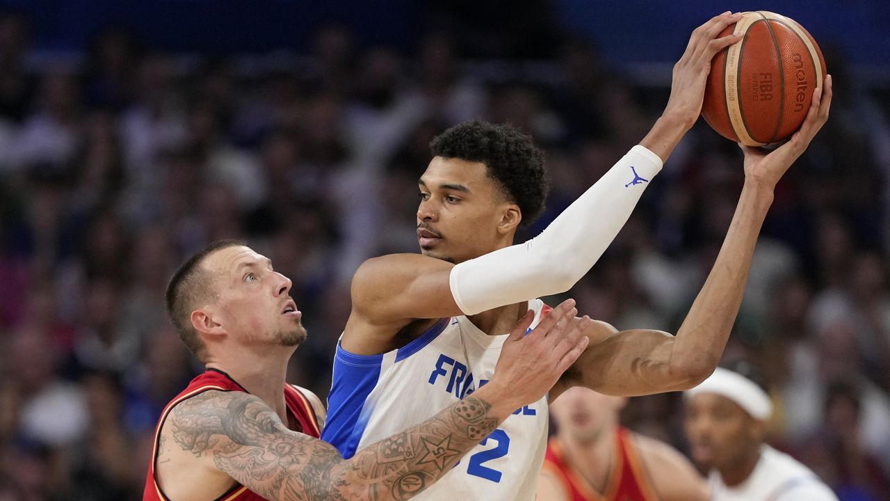 Daniel Theis, of Germany, reaches in on Victor Wembanyama, of France, in a men's basketball game at the 2024 Summer Olympics, Friday, Aug. 2, 2024, in Villeneuve-d'Ascq, France. (AP Photo/Mark J. Terrill)