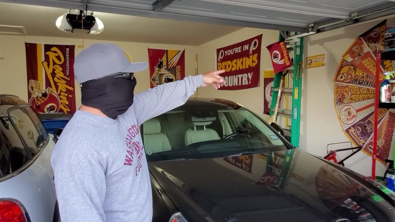 Brian Batres points at Washington NFL team memorabilia inside his garage (Spectrum News)