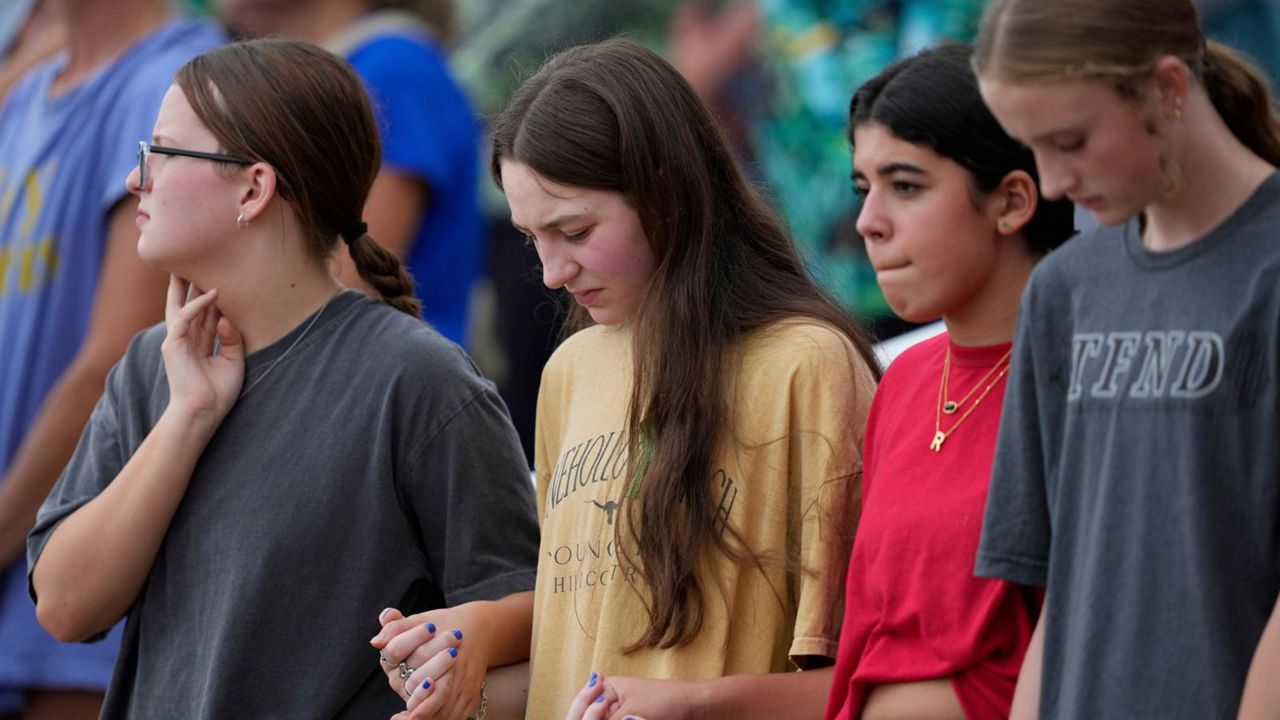 Attendees hold hands during a vigil for flooding victims at Tivy Antler Stadium on Wednesday, July 9, 2025, in Kerrville, Texas. (AP Photo/Ashley Landis)