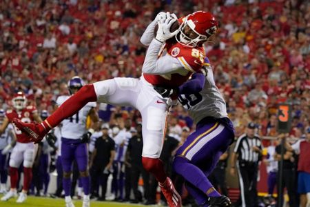 Kansas City Chiefs tight end Travis Kelce (87) catches a pass as Minnesota  Vikings safety Xavier Woods (23) and linebacker Nick Vigil (59) defend  during the first half of an NFL football