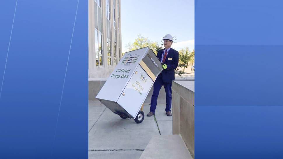 In this photo provided by Wausau Mayor Doug Diny, Diny uses a dolly to remove the city's lone drop box from in front of City Hall in Wausau, Wis., on Sunday, Sept. 22, 2024. (Doug Diny via AP)