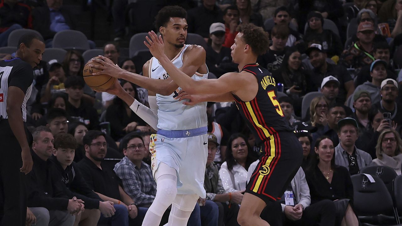 Atlanta Hawks guard Dyson Daniels (5) puts pressure on San Antonio Spurs center Victor Wembanyama, left, during the first half of an NBA basketball game in San Antonio, Thursday, Dec. 19, 2024. (AP Photo/Kin Man Hui)