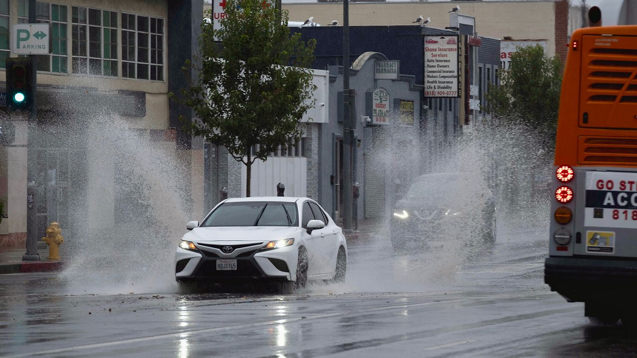 A vehicle splashes through puddles along a street starting to flood in the Van Nuys section of Los Angeles as a tropical storm moves into the area on Sunday, Aug. 20, 2023. Tropical Storm Hilary is no longer a hurricane but it's still packing what forecasters call "life-threatening" rain as it speeds up Mexico's Baja coast toward Southern California. (AP Photo/Richard Vogel)