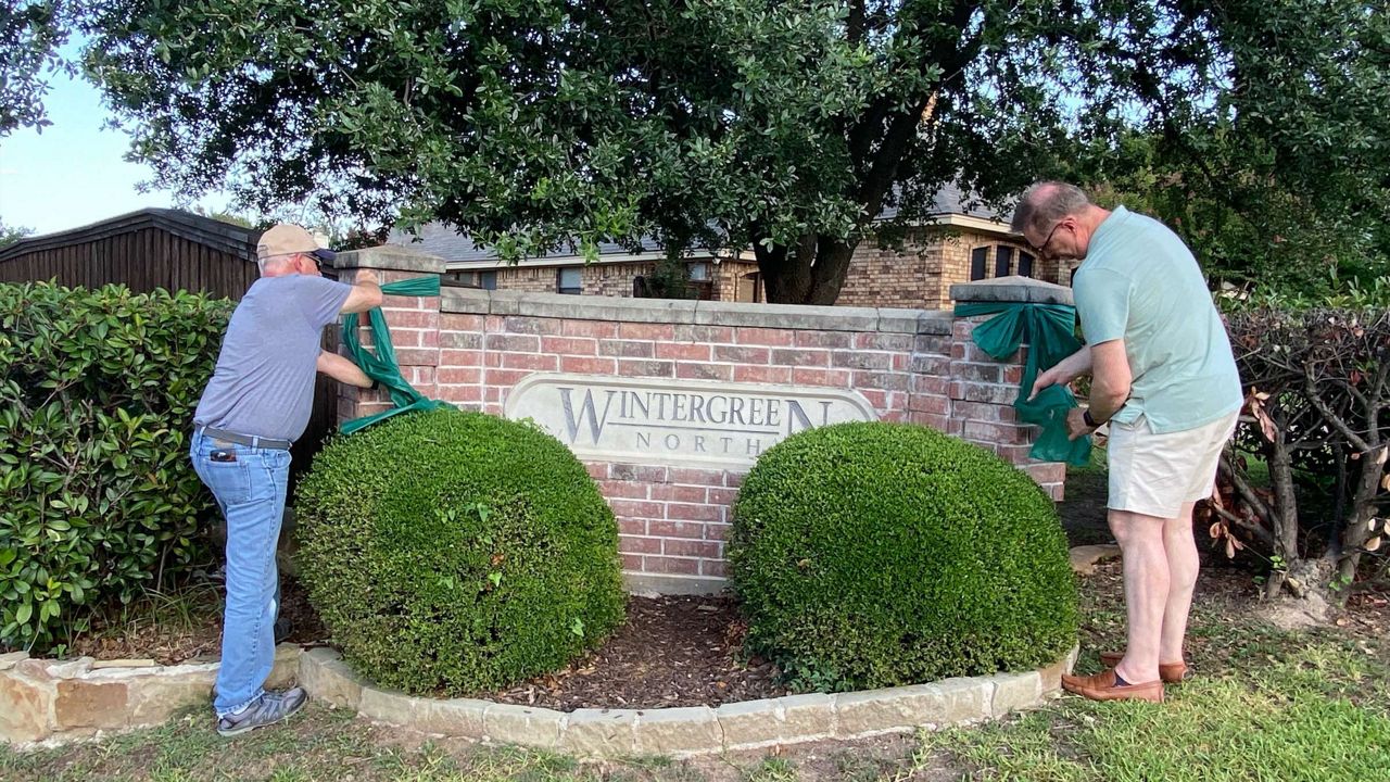 Men tying green ribbons around a sign for the Wintergreen North neighborhood in Tarrant County. (Courtesy Dana Greer)
