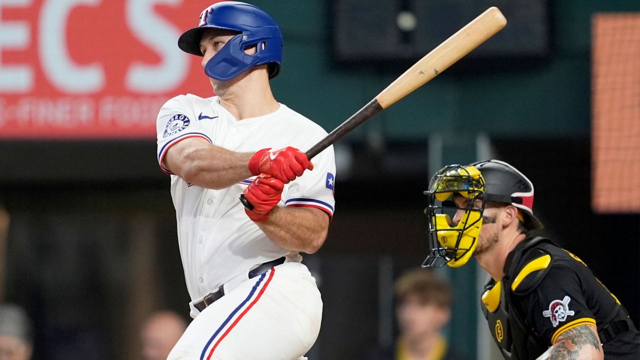 Texas Rangers' Wyatt Langford follows through on a run-scoring single as Pittsburgh Pirates catcher Yasmani Grandal, right, looks on in the ninth inning of a baseball game, Wednesday, Aug. 21, 2024, in Arlington, Texas. (AP Photo/Tony Gutierrez)