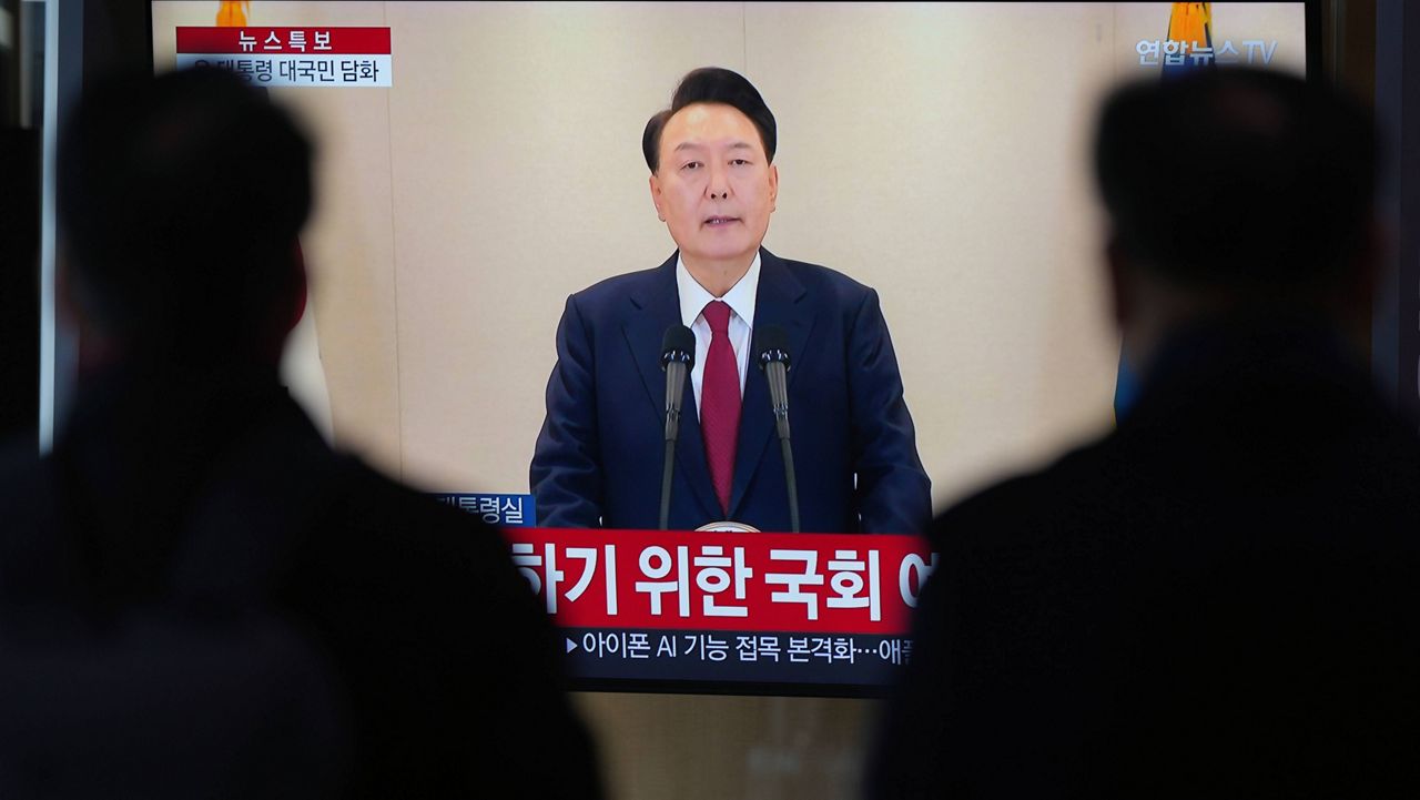 People watch a TV screen showing the live broadcast of South Korean President Yoon Suk Yeol's announcement at the Seoul Railway Station in Seoul, South Korea, Thursday, Dec. 12, 2024. (AP Photo//Lee Jin-man)