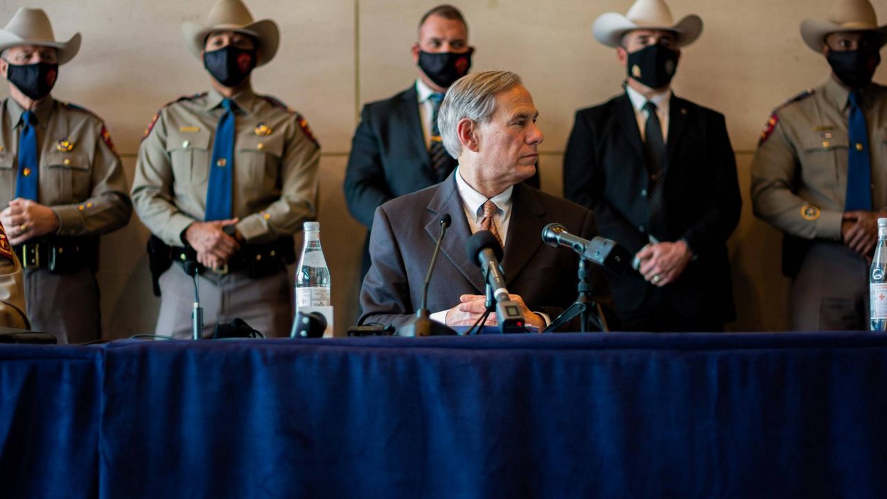 Texas Gov. Greg Abbott sits at a press conference while law enforcement lines the wall behind him. (Spectrum News 1/File)