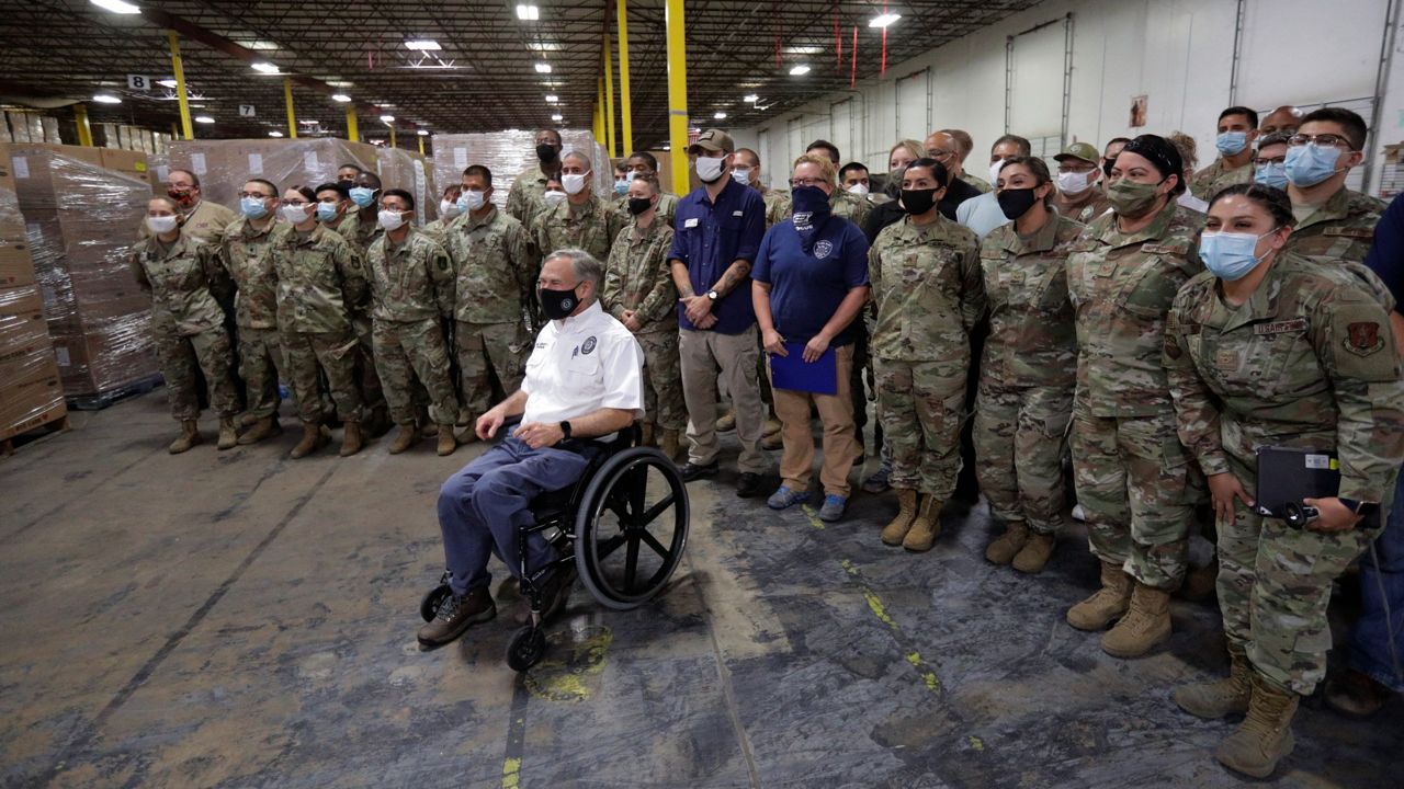 Texas Gov. Greg Abbott, foreground, poses for a photo with members of the National Guard during a visit to a Texas Division of Emergency Management Warehouse filled with Personal Protective Equipment, Tuesday, Aug. 4, 2020, in San Antonio. (AP Photo/Eric Gay)