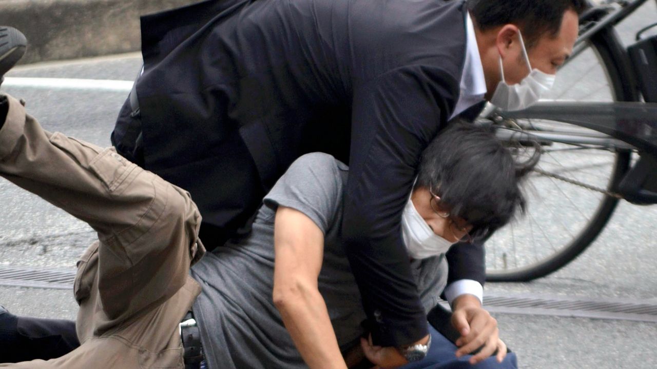 Tetsuya Yamagami, bottom, is detained Friday near the site of the Shinzo Abe shooting in Nara Prefecture, Japan. (Katsuhiko Hirano/The Yomiuri Shimbun via AP)