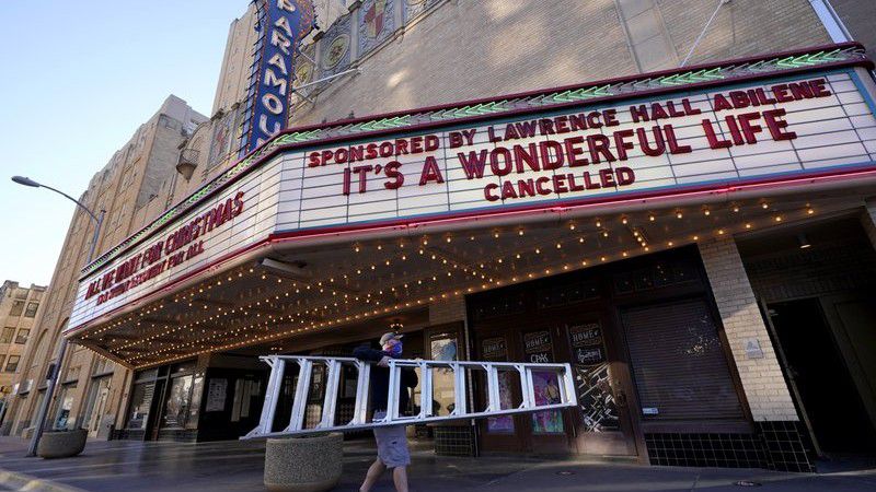Employee Grayson Allred walks away with a ladder after working on the front marquee at the Paramount Theatre on Wednesday, Dec. 16, 2020, in Abilene, Texas. (AP Photo/Tony Gutierrez)