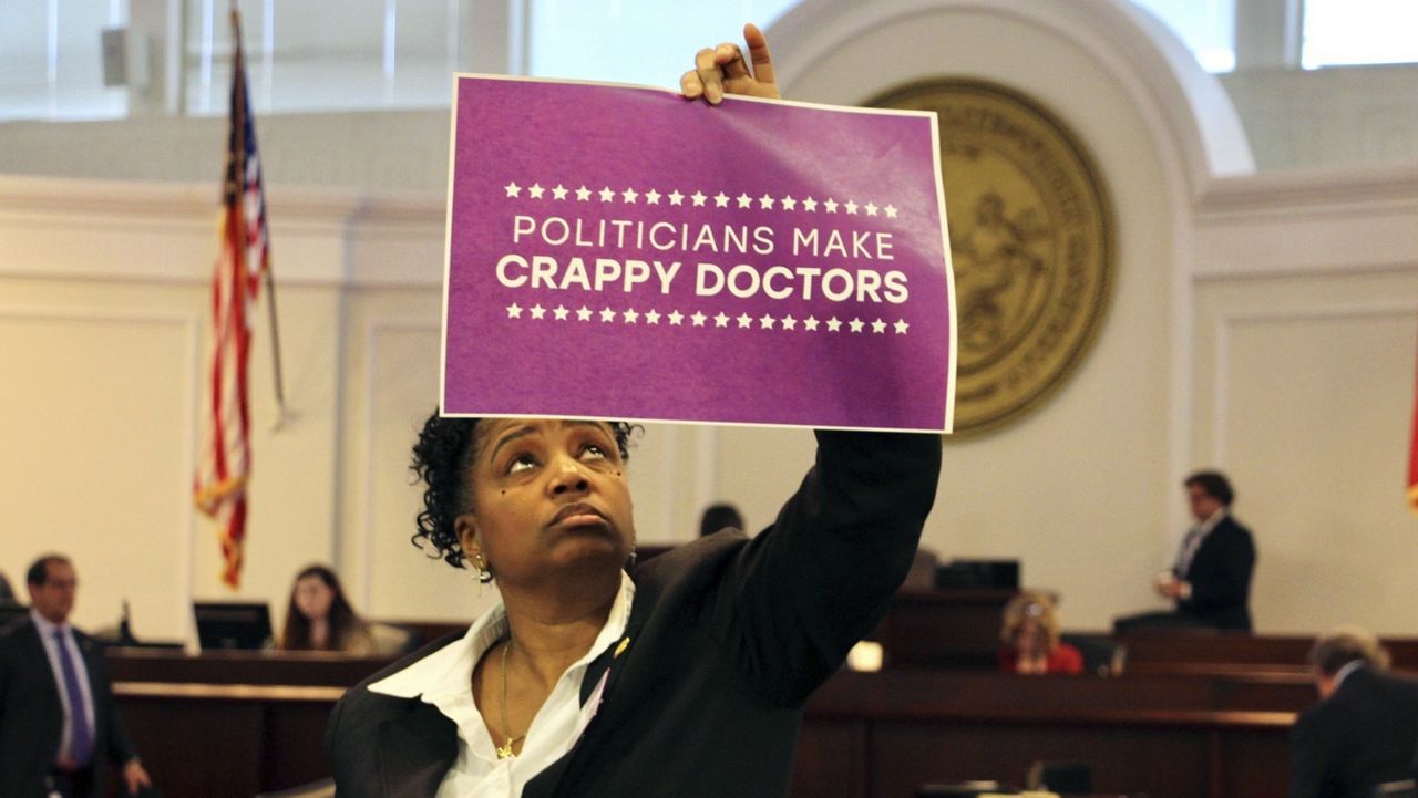 North Carolina state Sen. Kandie Smith, a Pitt County Democrat, holds up a sign that reads "Politicians Make Crappy Doctors" on the Senate floor in Raleigh, N.C., after the chamber voted to approve new abortion restrictions, Thursday, May 4, 2023. (AP Photo/Hannah Schoenbaum)