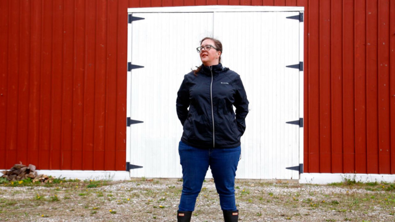 Alison Dreith stands in front of her barn in southern Illinois on Wednesday, April 13, 2022. Dreith works remotely for the Midwest Access Coalition, which pays for "practical support" for women seeking abortions. That includes things like air fare, gas money, hotel rooms or child care. Says Dreith, "I'm kind of a freak out first, calm down later kind of person is the big energy I have. So I really appreciate that I have something — no pun intended — like, really practical to do." (AP Photo/Martha Irvine)