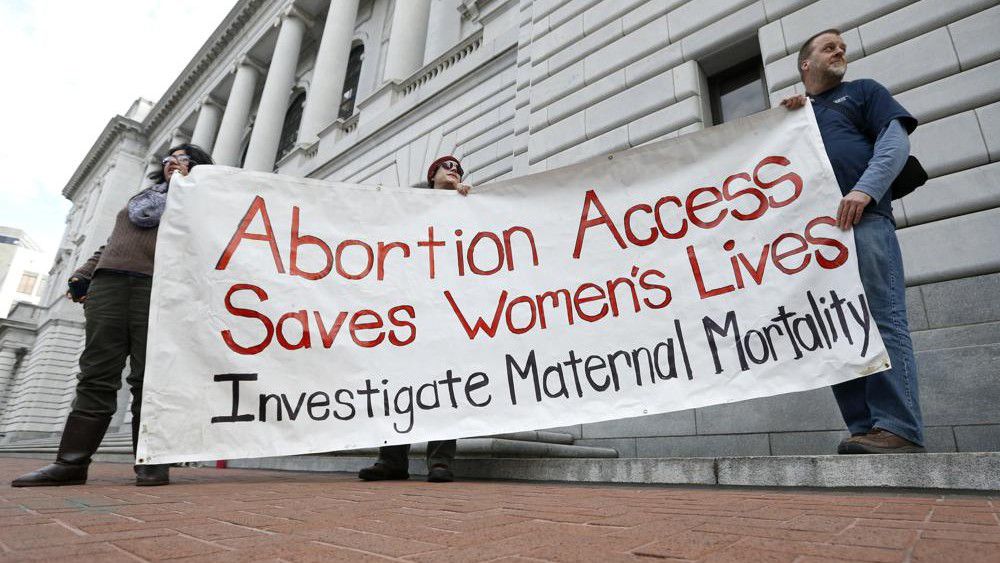 Bill Lambert, right, Phil Walk, center, and Brenda Serrato demonstrate outside of the 5th U.S. Circuit Court of Appeals on Jan. 7, 2015, in New Orleans. States with some of the nation's strictest abortion laws are also some of the hardest places to have and raise a healthy child, especially for the poor, according to an analysis of federal data by The Associated Press. (AP Photo/Jonathan Bachman, File)