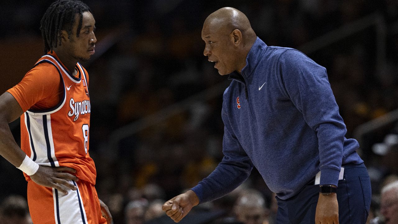 syracuse basketball coach adrian autry speaks with player elijah moore, who's wearing an orange syracuse basketball uniform