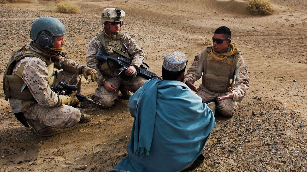 In this Friday, Dec. 11, 2009, file photo, United States Marine Sgt. Isaac Tate and Cpl. Aleksander Aleksandrov interview a local Afghan man with the help of a translator More than 200 Afghans were due to land Friday in the United States in the first of several planned evacuation flights for former translators and others as the U.S. ends its nearly 20-year war in Afghanistan. (AP/Kevin Frayer)