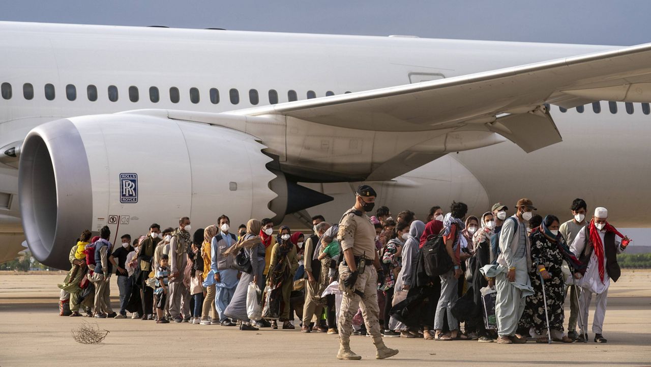 Afghan people walk after disembarking a plane at the Torrejon military base in Madrid on Monday. (AP Photo/Andrea Comas)