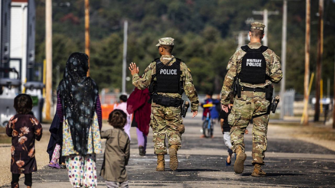 U.S. Military Police walk past Afghan refugees at the Village at the Ft. McCoy U.S. Army base on Thursday, Sept. 30, 2021 in Ft. McCoy, Wis. The base is one of two still hosting Afghan evacuees in the United States as of Feb 4. (Barbara Davidson/Pool Photo via AP)