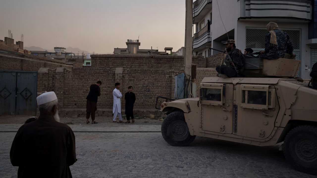  Afghans watch as Taliban fighters ride atop a humvee after detaining four men who got involved in a street fight in Kabul, Afghanistan, Tuesday, Sept. 21, 2021. (AP Photo/Felipe Dana)