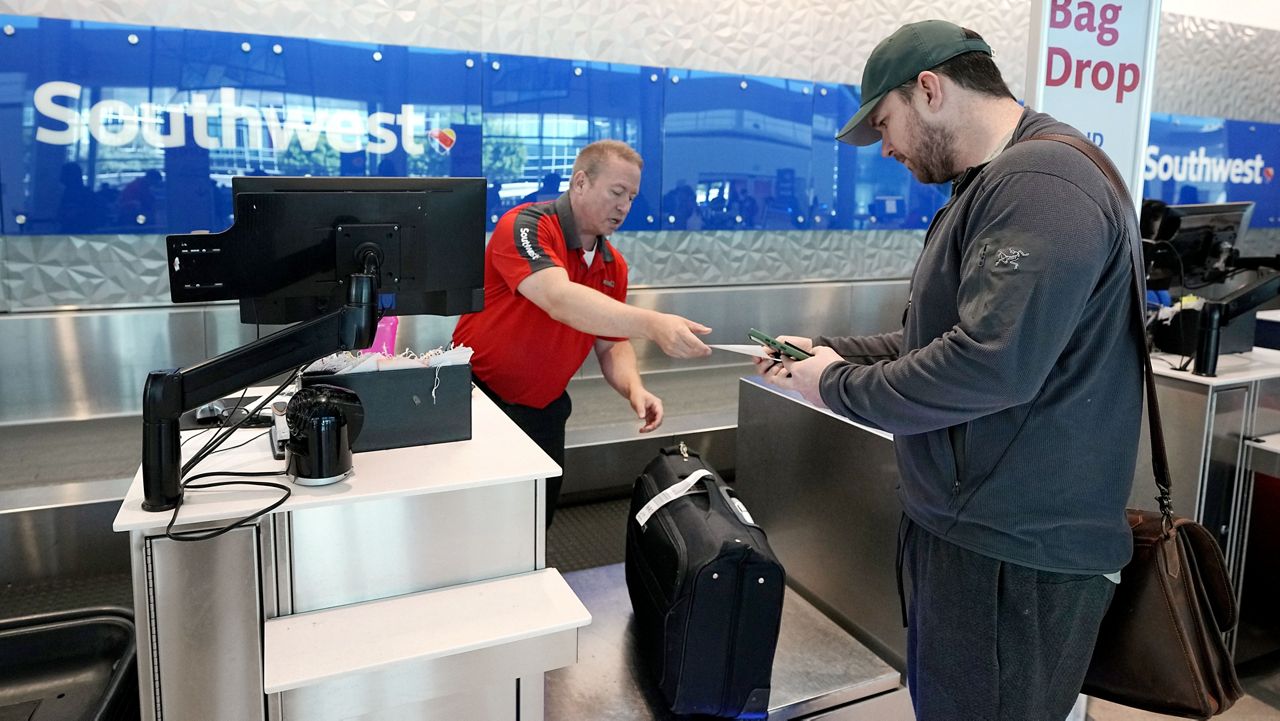 Chris Odom, right, checks his bags with a customer service representative at the Southwest ticketing gate at Love Field Airport in Dallas on May 19. (AP Photo/Tony Gutierrez)