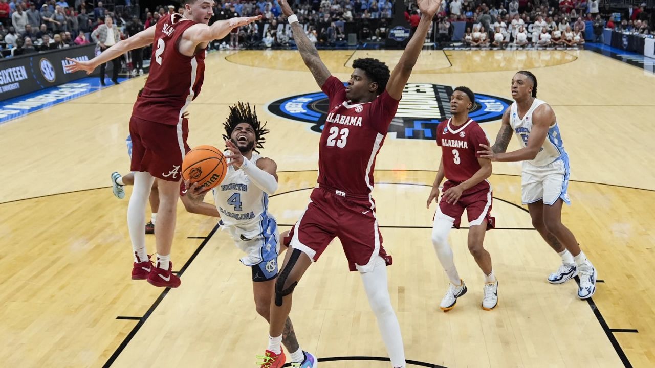 North Carolina guard RJ Davis (4) drives to the basket between Alabama forward Grant Nelson (2) and forward Nick Pringle (23) during the second half of a Sweet 16 college basketball game in the NCAA tournament Thursday, March 28, 2024, in Los Angeles. (AP Photo/Ashley Landis)