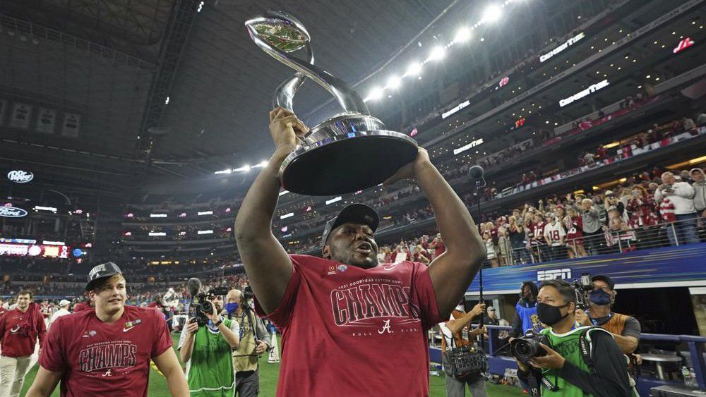 Alabama defensive lineman Byron Young carries the winner's trophy after the Cotton Bowl NCAA College Football Playoff semifinal game against Cincinnati, Friday, Dec. 31, 2021, in Arlington, Texas. Alabama won 27-6. (AP Photo/Jeffrey McWhorter)