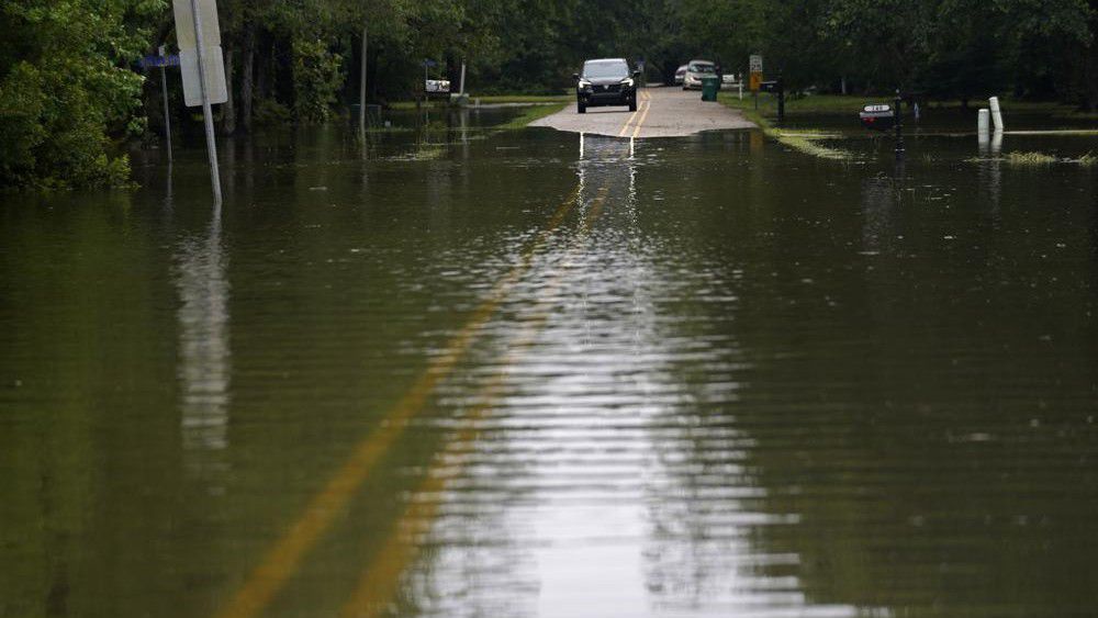 A car stops in front of neighborhood flooding after Tropical Storm Claudette passed through, in Slidell, La., Saturday, June 19, 2021. (AP Photo/Gerald Herbert)