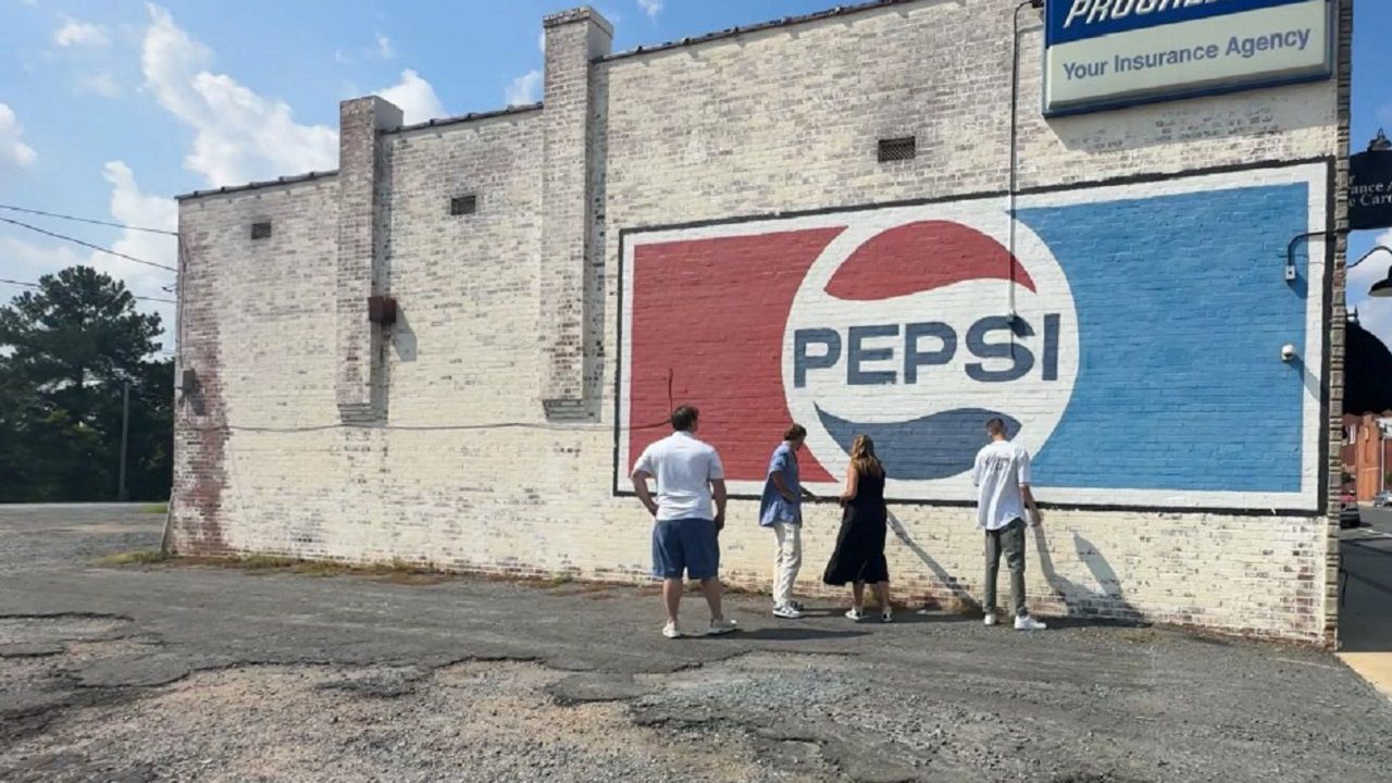 The Williams brothers and their parents are in front of a Pepsi sign in downtown Albemarle. This is the first ghost sign the Williams brothers restored. (Spectrum News 1/Jennifer Roberts)