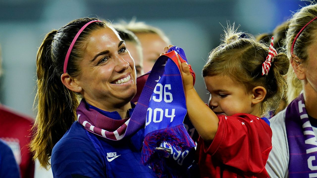 United States' Alex Morgan holds her daughter, Charlie, as she listens to Cindy Parlow Cone, president of the U.S. Soccer Federation, speak during an event with the federation, U.S. Women's National Team Players Association and the U.S. National Soccer Team Players Association at Audi Field in Washington, Tuesday, Sept. 6, 2022. (AP Photo/Julio Cortez, File)