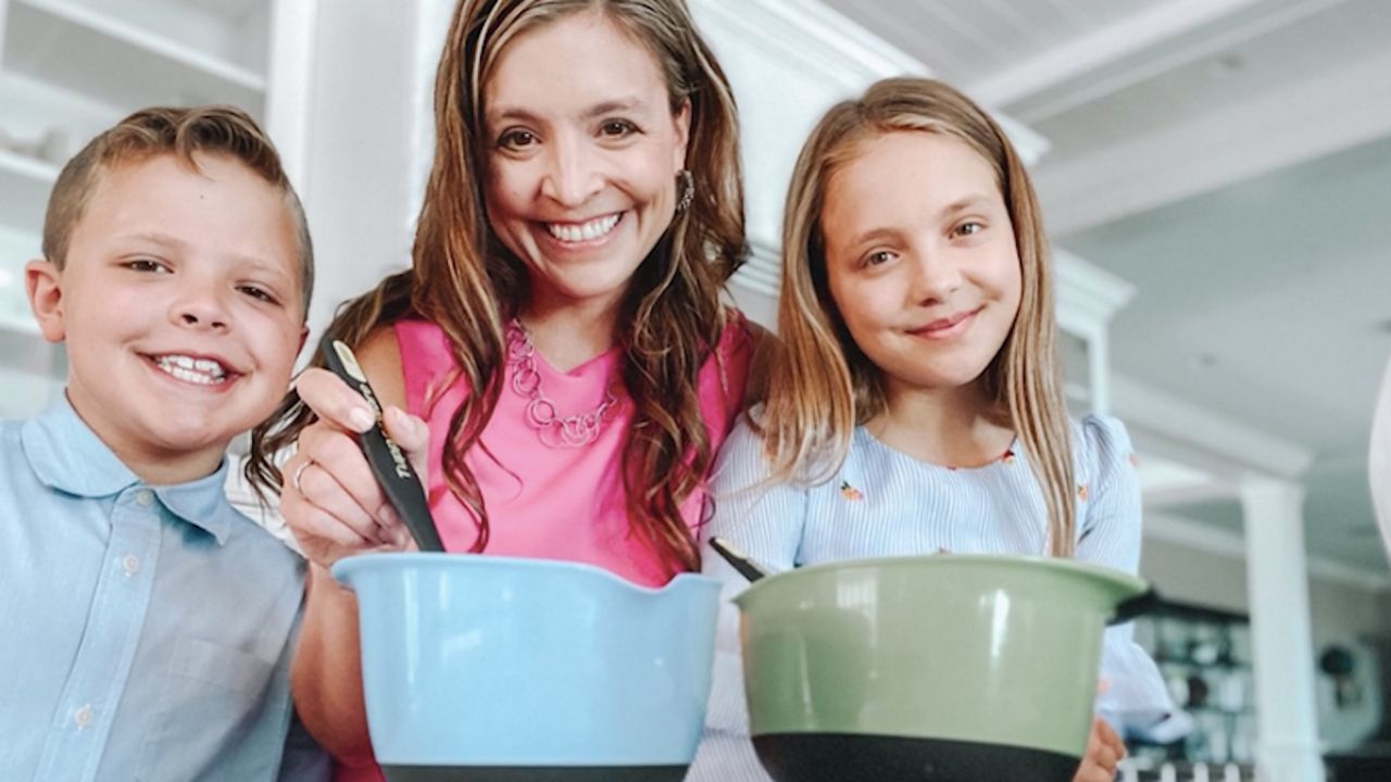 A woman and a girl and boy together with a cooking bowl
