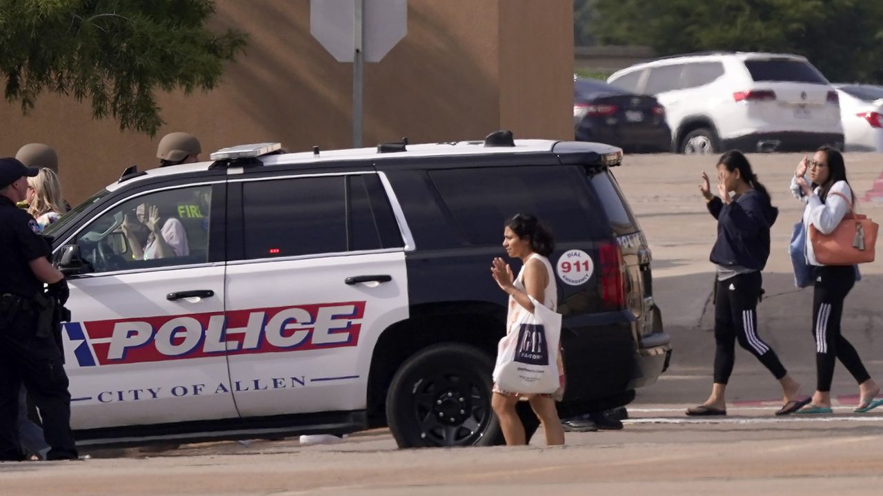 People raise their hands as they leave a shopping center after a shooting, Saturday, May 6, 2023, in Allen, Texas. (AP Photo/LM Otero)
