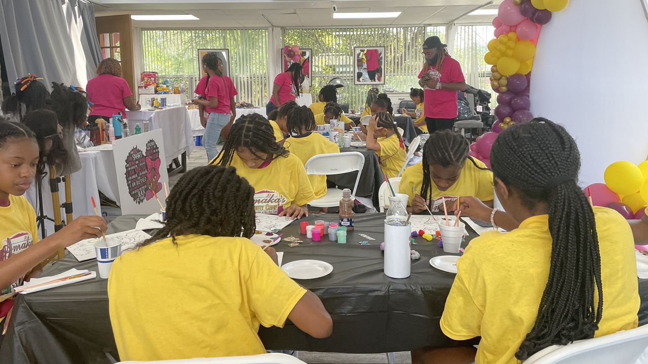 Young girls are painting at Amaka's Beauty Camp in Durham.