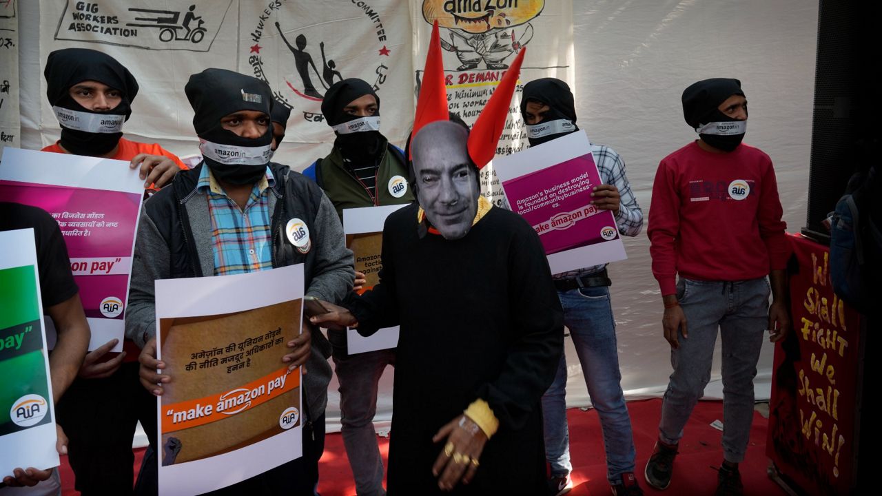 A woman dressed as Jeff Bezos and other Gig Workers Association and Amazon Warehouse workers participate Friday in a protest in New Delhi. (AP Photo/Manish Swarup)