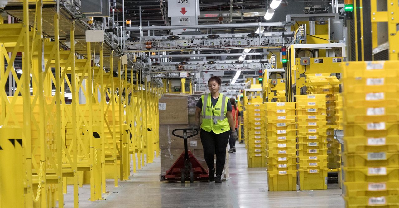 In this Wednesday, Dec. 5, 2018, photo an employee moves merchandise in Amazon fulfillment center on Staten Island borough of New York. (AP Photo/Mary Altaffer)