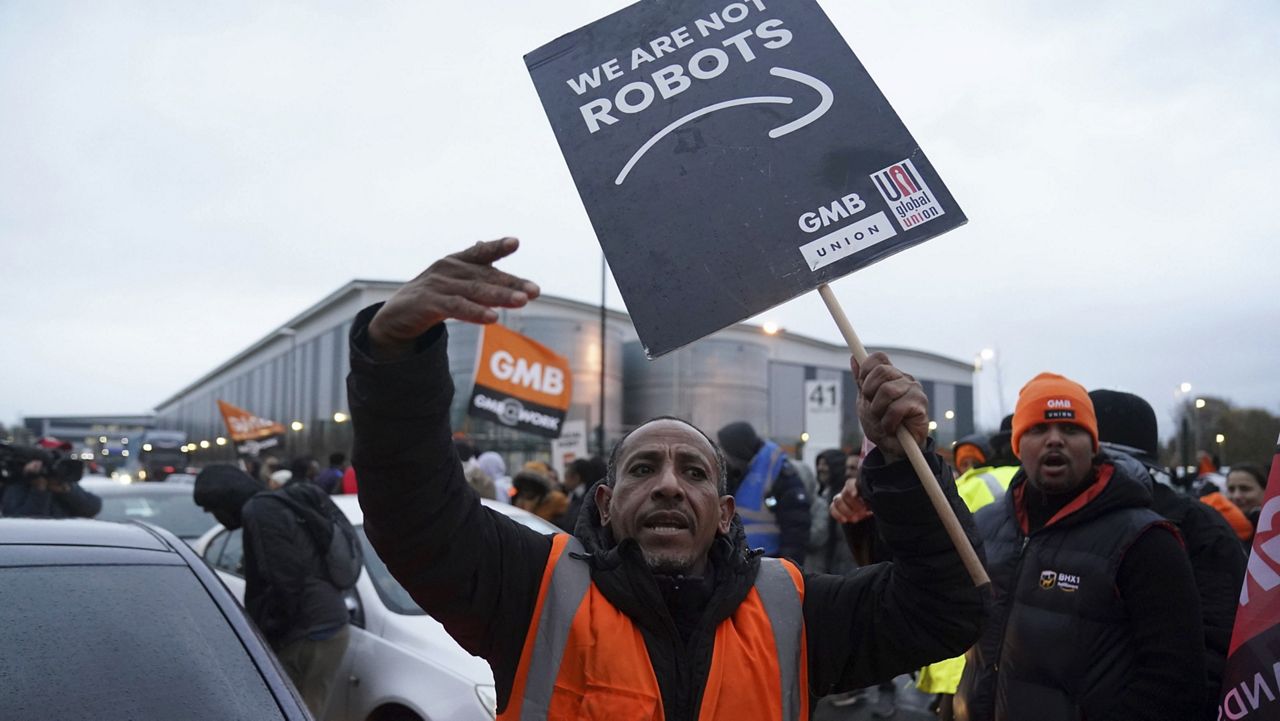 An Amazon employee gestures on a GMB union picket line in Coventry, England, as workers take part in a strike in their long-running dispute over pay on Friday, Nov. 24, 2023. (Jacob King/PA via AP)