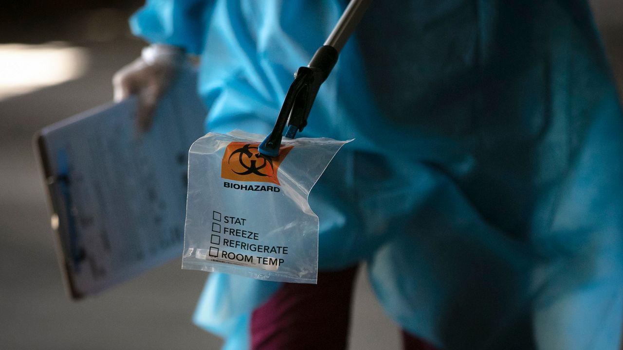 A physician assistant carries a nasal swab sample using a grabber at a COVID-19 drive-through testing site set up at the Anaheim Convention Center in Anaheim, Calif., Thursday, July 16, 2020. Rising coronavirus infections across dozens of states are threatening the U.S. economic recovery, forcing businesses and consumers to freeze spending and keeping the unemployment rate stubbornly high. (AP Photo/Jae C. Hong