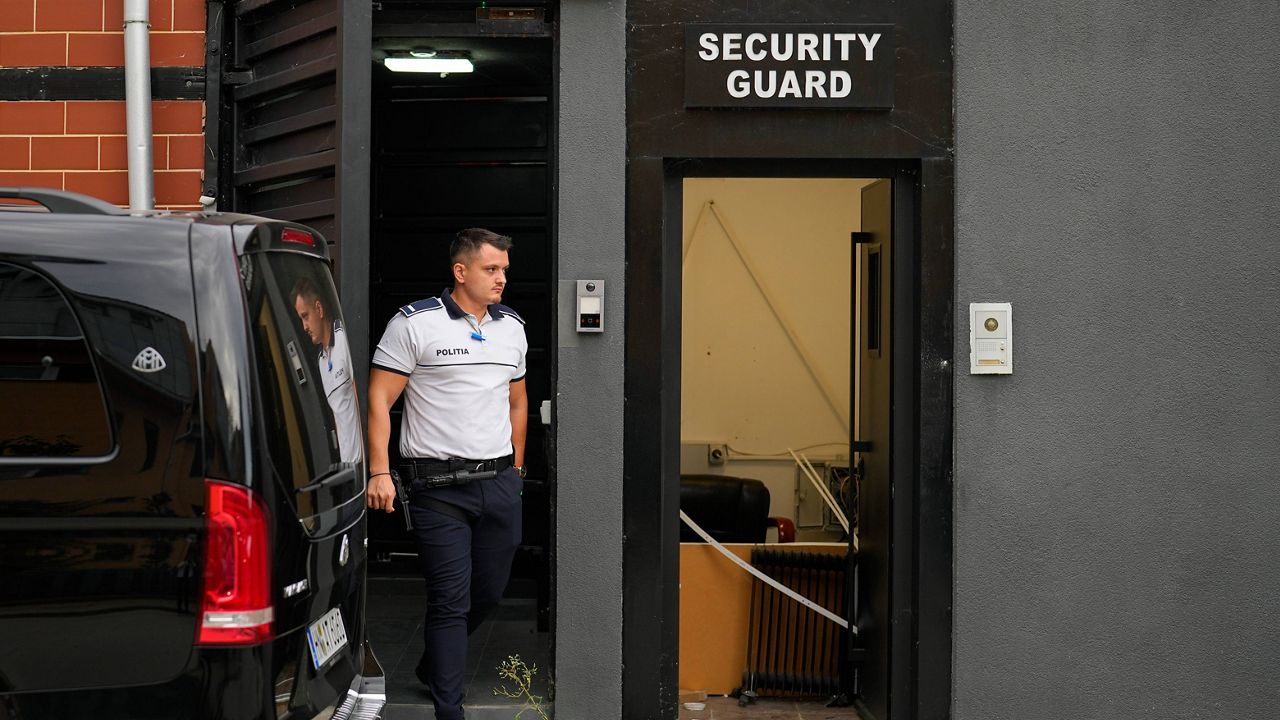 A police officer exits the residence of social media personality Andrew Tate during an early morning search raid, on the outskirts of Bucharest, Romania, Wednesday, Aug. 21 2024. (AP Photo/Vadim Ghirda)