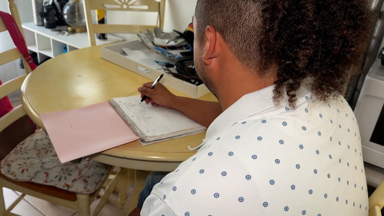Pinellas Park resident Jerome Santos planning his budget at home. (Spectrum Bay News 9/Erica Riggins)