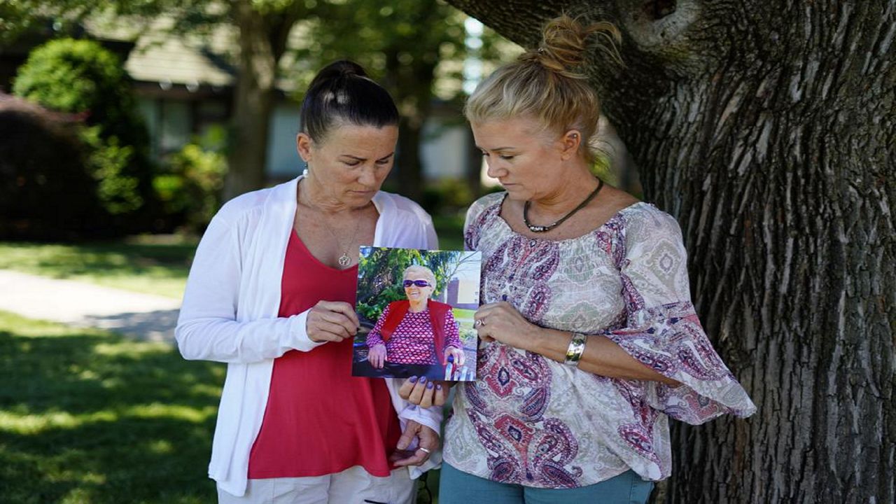 Angela Ermold, right, and her sister, Denise Gracely, hold a photo of their mother, Marian Rauenzahn, Thursday, June 17, 2021, in Fleetwood, Pa. Pandemic restrictions are falling away almost everywhere — except inside many of America’s nursing homes. “They have protected them to death,” said Gracely. (AP Photo/Matt Slocum)